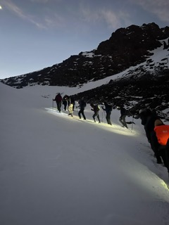 Trekkers climbing a snowy slope by headlamp before dawn on the Toubkal summit ascent