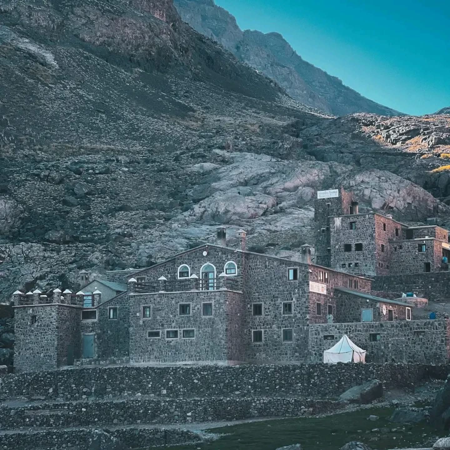 Toubkal Refuge stone buildings at the foot of steep rocky peaks