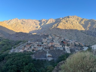 Berber village set in a green valley beneath sunlit rocky Atlas ridges
